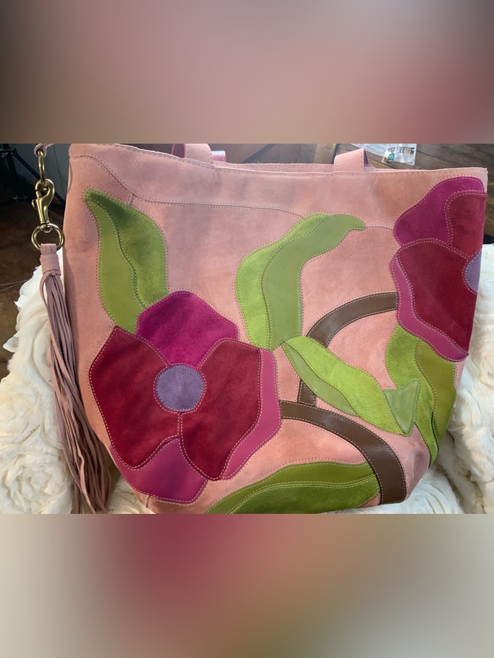 Coach Poppy for Peace suede tote features a prominent floral applique design